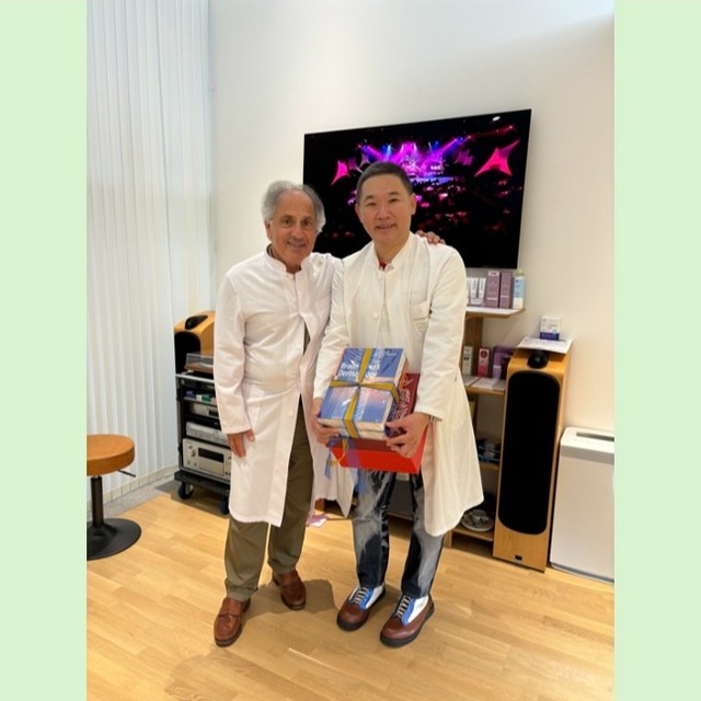 ”教授クリニックご訪問”
ドイツのミュンヘン大学皮膚科に留学していた時の教授が僕のクリニックにご訪問して、教授も執筆に携わった皮膚科の成書を頂きました。
ミュンヘン大学では、大昔から現在までお昼の時間帯に「大回し」という診察スタイルを行っています。
入院患者様においては、病棟医と教授が一緒になって「病棟回診」をして患者様の治療方針について議論しますが、「大回し」は、その外来版に相当します。お昼の時間帯に、広いカンファレンスルームに多いときは30人以上の皮膚科医が集まります。担当医が当日診断・治療に難渋する外来患者様の症例提示をして、その後実際の外来患者様が登場します。そして多くの医師が集まって患者様の皮膚病変を診察して、その後皮膚病変についてみんなでディスカッションします。多くの医師に診られて恥ずかしいとい思うかも知れませんが、ほとんどの患者様は多くの医師に診察して頂いたことに感謝の言葉を残していきます。
症例も豊富なミュンヘン大学ですので、このような成書ができるのも納得します。
自分もクリニックで患者様を診たときに、「大回し」の時のように多くの鑑別疾患が挙げられるように、日々勉強に励みたいと思っています。
院長
#トータルスキンケア・クリニック銀座 #銀座 #東銀座 #皮膚科 #クリニック #ミュンヘン大学 #ご訪問 #成書 #築地 #銀座松竹スクエア #大回し #回診